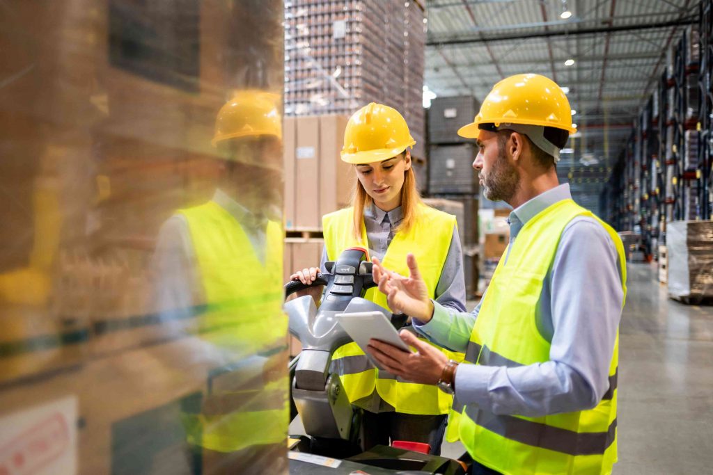 Two colleagues with a tablet next to a pallet truck in a warehouse